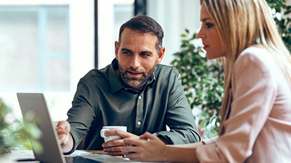 Man and woman looking at laptop at a table